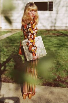 a woman standing in front of a house holding a purse