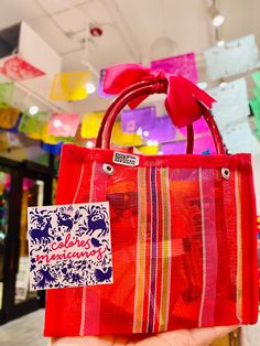 a hand holding a red bag with a bow on it in front of a store