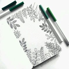 two markers and some pens on top of a notebook with an image of plants in it