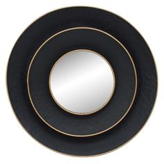 two black and gold plates sitting next to each other on a white surface with a round mirror in the middle