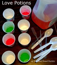 there are many cups and spoons with colored liquid in them