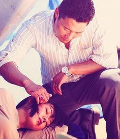 the man is helping the woman to put on her shoelaces while sitting down