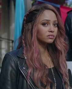 a close up of a person wearing a leather jacket and braids on her hair