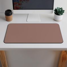 a computer monitor sitting on top of a desk next to a cup and potted plant