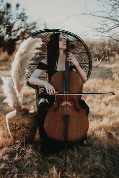 a woman sitting in a chair holding a cello