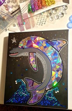 a piece of art that looks like a dolphin is surrounded by beads and other crafting supplies