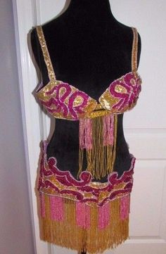 a mannequin wearing a pink and gold dress with fringes on it's back