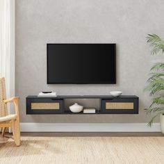 a flat screen tv mounted to the side of a wall next to a chair and potted plant