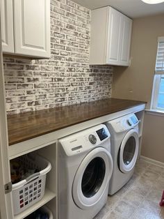 a washer and dryer in a small laundry room with brick wall behind it