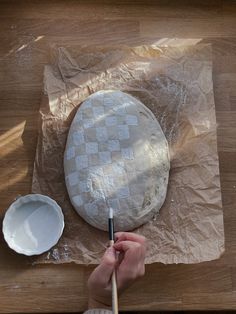 a person is making a pie on a wooden table with plastic wrap around the edges