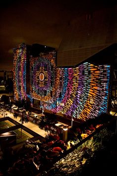 an illuminated building in the middle of a city at night with lights on it's sides