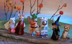 five miniature mice dressed in costumes and hats, standing on a ledge next to an apple tree