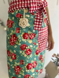 a woman wearing a green apron with red and white flowers on it