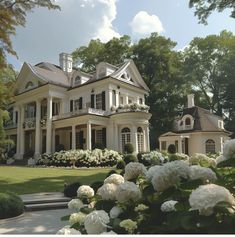 a large white house sitting in the middle of a lush green field