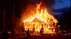 a house on fire with people around it