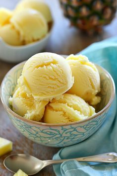 three scoops of ice cream in a blue bowl with pineapple on the side