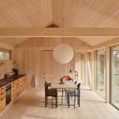 a kitchen with wooden walls and flooring next to a dining room table surrounded by chairs