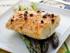 a white plate topped with fish and asparagus