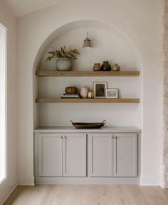 a white room with shelves and vases on top of it, along with other items