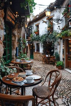 a cobblestone street with tables and chairs in front of an alleyway cafe