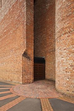 a brick building with an open door in the center and cobblestone pavement around it