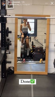 a woman is taking a selfie in the mirror while riding a stationary exercise bike