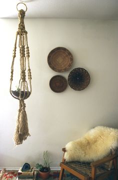 a room with three hanging baskets on the wall next to a chair and rug in front of it