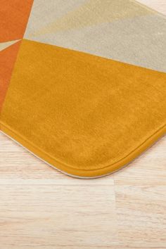 an orange and grey area rug on top of a wooden floor next to a cell phone