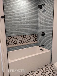 a white bath tub sitting under a window next to a toilet and shower head in a bathroom