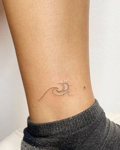 a woman's ankle with a small sun and wave tattoo on her left side