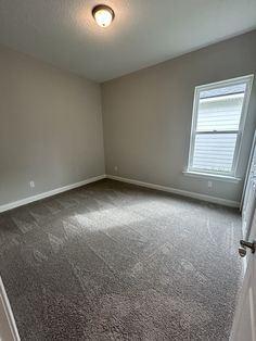 an empty room with carpet and two windows