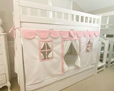 a white bunk bed with pink trim and curtains