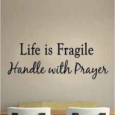 a dining room table with two chairs and a wall decal that says life is fragile handle with prayer