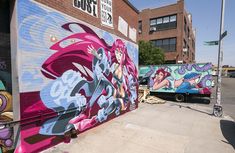 a truck parked in front of a building with graffiti on it's side wall