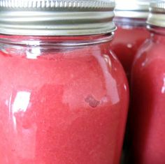 three jars filled with red liquid sitting next to each other