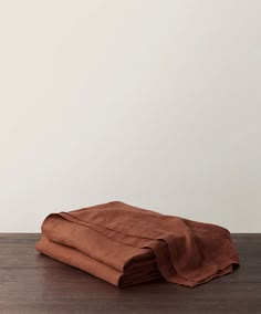 two folded brown linens sitting on top of a wooden table next to a white wall