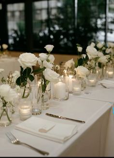 the table is set with white flowers and candles