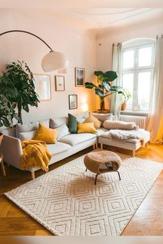 a living room filled with lots of furniture and plants on top of a rug in front of a window