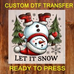 a snowman wearing a santa hat and scarf with trees in the background that says, custom dtf transferer let it snow ready to press