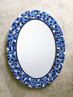 a round mirror with blue and white mosaic tiles on the rim, hanging on a wall