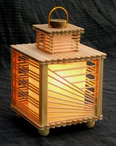 a small wooden lantern sitting on top of a black surface with a lit candle in it