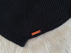 there is a black knitted hat with an orange tag on it