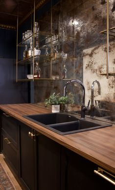 a kitchen with wooden counter tops and black cabinets in front of a wall mounted shelving unit