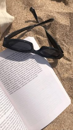 an open book with sunglasses on top of it next to a pair of black glasses