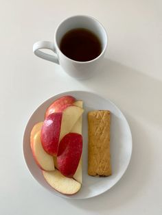 an apple and peanut butter sandwich on a plate next to a cup of coffee