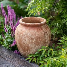 a large vase sitting on top of a wooden table next to flowers and greenery