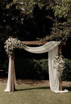 an outdoor wedding ceremony with white flowers and draping