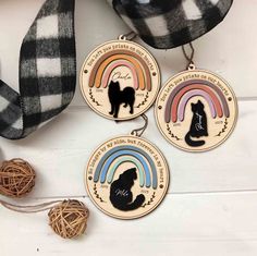 three medals with cats and rainbows on them next to some twine balls