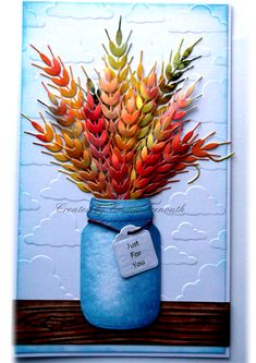 a card with a blue mason jar filled with colorful flowers on top of a wooden table