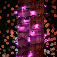 purple lights are strung up on a wooden post